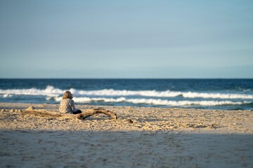 Mature age Woman sitting on the beach looking out to sea Contemplating life in the evening...