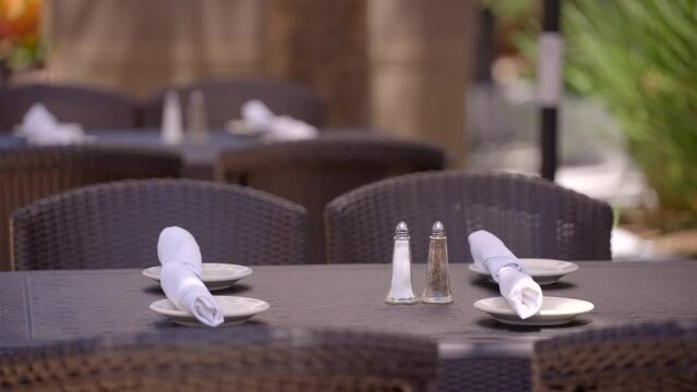 Restaurant table setup ith salt pepper and rolled up silverware in napkins. 4k 24p prores with bokeh blurry background