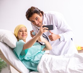 Young handsome doctor visiting female oncology patient