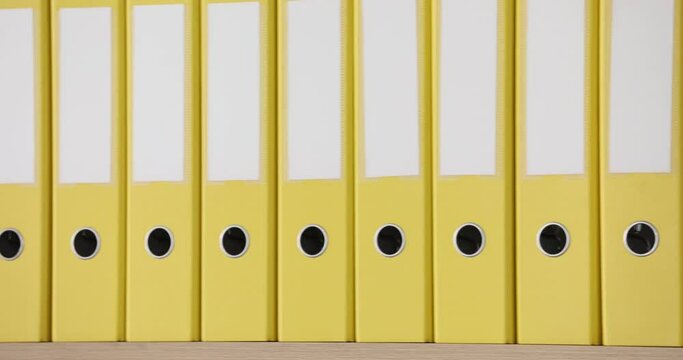 Yellow folders stand in a row, close-up. Stationery, office supplies, slowmotion