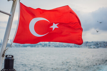 Turkish flag flying in the wind against the background of the sea and the coast