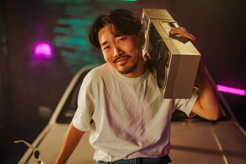 Cool Asian man with boombox outdoors.