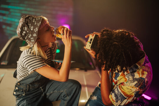 Man photographing woman eating outside.