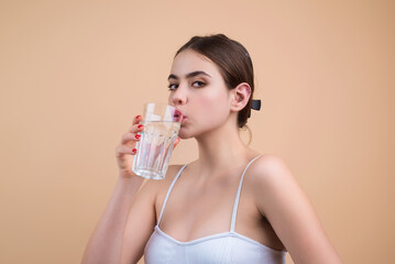 Woman drinking fresh water, isolated on studio background. Girl holds glass of water. Mineral water...