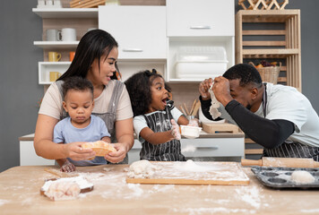 Fototapeta premium Happy African American father and Asia mother with daughter and son cooking break or bakery at kitchen at home 