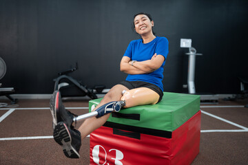 Happy Asia woman with prosthetic leg exercise at gym or fitness	