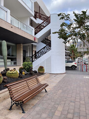 Wooden bench on the paved sidewalk near residential building.