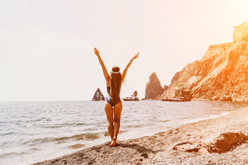 Woman beach vacation photo. A happy tourist in a blue bikini enjoying the scenic view of the sea and volcanic mountains while taking pictures to capture the memories of her travel adventure.