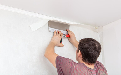 A worker pastes wallpaper on the walls in a room
