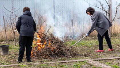 A boy and a woman are burning dry grass in the garden © schankz