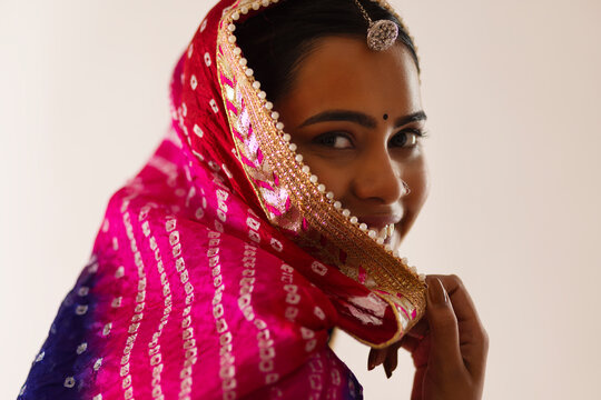 Close-up portrait of a cheerful Rajasthani young woman against white background