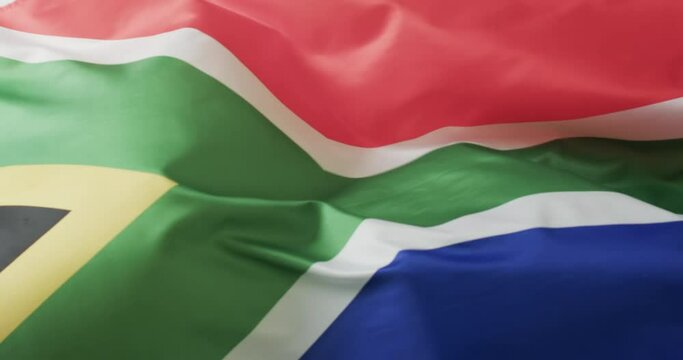 White rugby ball rolling over waving flag of south africa with copy space, in slow motion