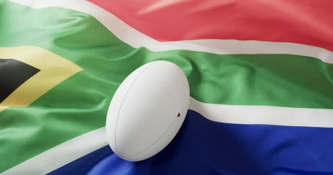 White rugby ball over waving flag of south africa with copy space, in slow motion
