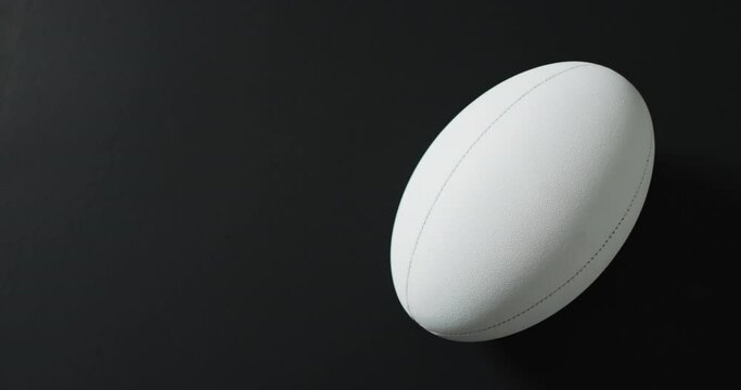 White rugby ball on black background with copy space, slow motion