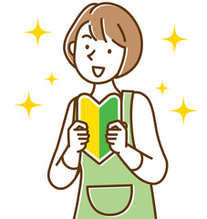 笑顔で初心者マークを持つエプロン姿の若い女性