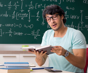 Young male student mathematician in front of chalkboard