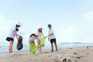 Volunteers of boys and girls happily picking up trash on the beach.