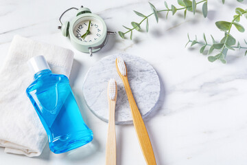 Oral health care product, bamboo toothbrush and mouthwash with clock on marble background - obrazy, fototapety, plakaty