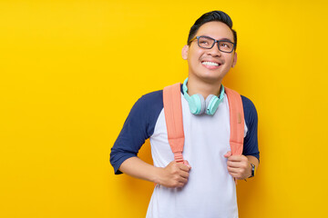 Cheerful young Asian man student in casual clothes backpack looking on empty space, new...