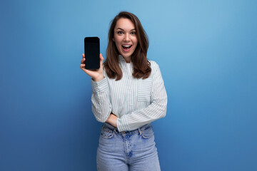 pretty young brunette woman in shirt showing smartphone mockup on studio background