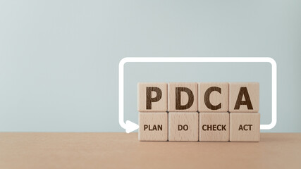 PDCA text ,means Plan Do Check Act, on wooden cube block with loop line including copy space. For...