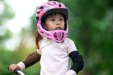 4 years old little girl with helmets practicing balance bike, looking at someone, kids with outdoor sports