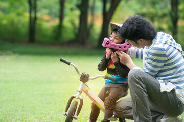 Father or trainer puts on a helmet for safety before practicing, 4 years old girl riding a balance bike, kids with outdoor sports