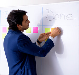 Young handsome employee in front of whiteboard with to-do list