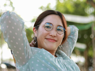 Red-haired woman in green shirt and eye care glasses sitting happy smiling looking outdoor