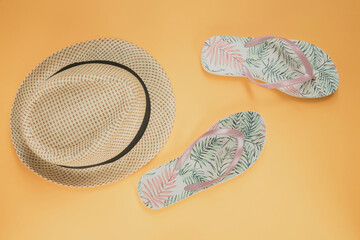 Hat and flip flops on yellow background. Vacation concept.