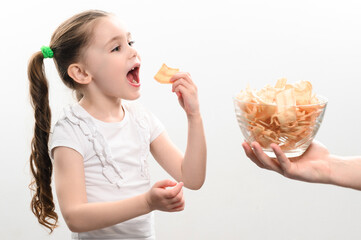 Little girl is given a big bowl of chips snacks with lard, white background portrait of little girl...