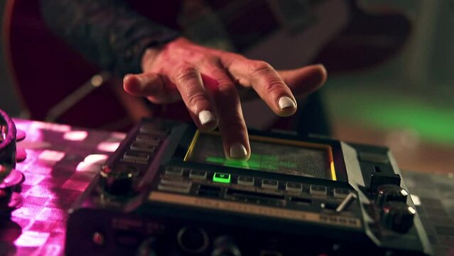 Person adjusting the amplifier of the bass guitar playing at a concert