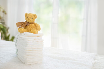 Cute teddy bear sitting on diapers stack