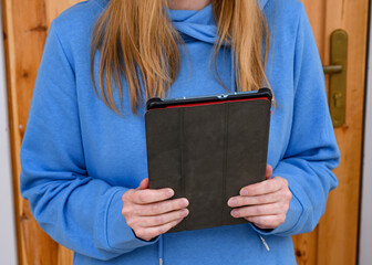 Ruda dziewczyna w niebieskiej bluzie prowadzi wideorozmowę przez tablet  - obrazy, fototapety, plakaty