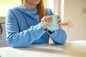 Kobieta siedząca w kafejce trzymająca kubek z herbatą 