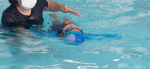 Little girl learning to swimming with .backstroke.