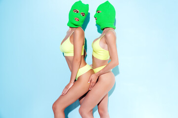 Two beautiful sexy women in green underwear. Models wearing bandit balaclava mask. Hot seductive...