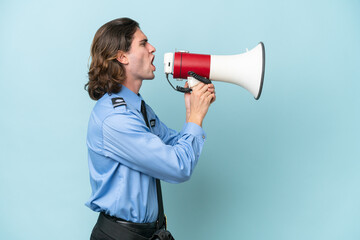 Young police caucasian man isolated on blue background shouting through a megaphone