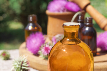 Burdock  flower heads, bottle of infusion. Concrept of Herbal or homeopathy medicine. Flower essential oil. Herbal medicine. Side view, copy space.      