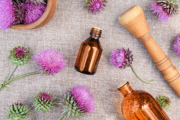 Burdock  flower heads, bottle of infusion. Concrept of Herbal or homeopathy medicine. Flower essential oil. Herbal medicine. Top view, flat lay.
