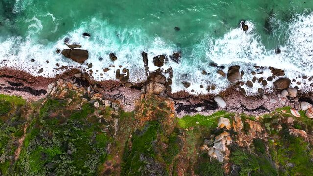South Africa rugged coastline small beach town Smitswinkel Bay Cape of Good Hope Simon's Town aerial drone cinematic homes surf wave green lush spring summer deep aqua blue ocean up motion