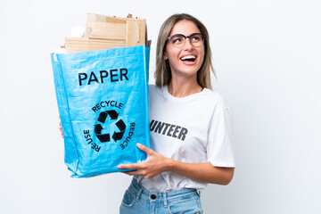 Young pretty Uruguayan woman holding a recycling bag full of paper to recycle isolated on white chroma background looking up while smiling