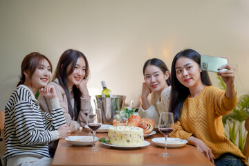 Asian sister friends making selfie and smiling with smartphone. celebrating with Birthday cake.