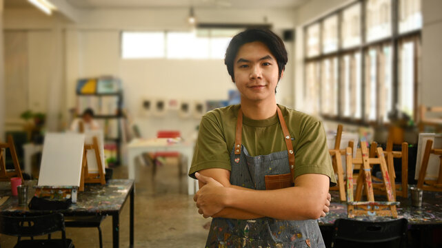 Portrait of asian man artist smiling confident, standing with arms crossed in art studio. Art, creativity, hobby, activity concept