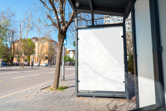 Bus stop with a billboard mockup, advertising space in white. Street in background