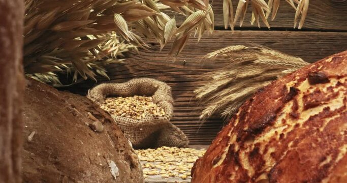 Loaves of bread with grains and ears on wooden table