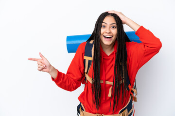 Hiker teenager girl with braids over isolated white background surprised and pointing finger to the...