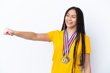 Teenager girl with braids and medals over isolated pink background giving a thumbs up gesture