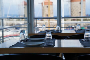 Restaurant interior  and  Medieval Windmills in Mandraki Harbour at the background, Island Rhodes, Greece