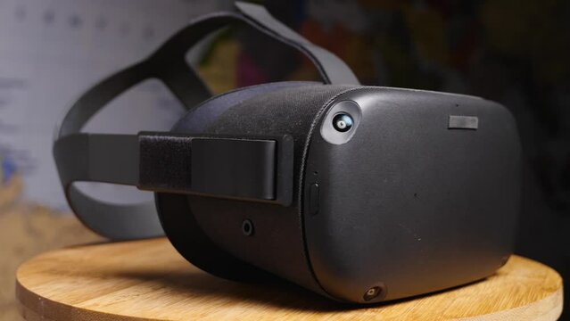 Black virtual reality glasses with four cameras on a wooden board against a world map. The camera flies around. VR helmet close-up. Parallax effect